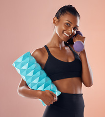 Image showing Smiling, healthy and slim female fitness instructor, holding weights and exercise equipment or tools for workout. Beautiful woman athlete with a fit body in gym sportswear against studio background