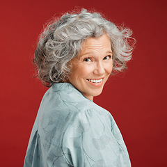 Image showing .. Confident, happy and smiling senior woman feeling playful and cheerful while posing against red studio background. Portrait of a beautiful, older and retired lady looking back with grey hair.