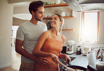 Image showing Romantic, happy and young couple cooking dinner food and hug on a home date in a kitchen. Smiling dating partners relax feeling happiness, romance and love spending time at their house or apartment