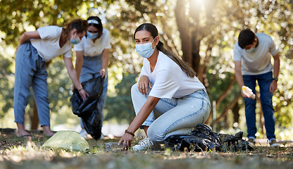 Image showing Covid, volunteer and charity with a young woman doing community service and cleaning up the environment with people in the background. Portrait of an eco friendly environmentalist picking up trash