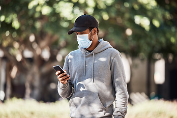 Image showing Man looking at phone in nature park, wearing face mask to prevent risk of covid and reading a text message online. Guy standing in garden outside, typing on social media and looking for gps location