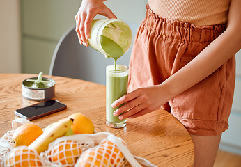 Image showing Closeup of a female pouring green healthy smoothie to detox, drinking vitamins and nutrients. Woman nutritionist having a fresh fruit juice to cleanse and provide energy for healthy lifestyle