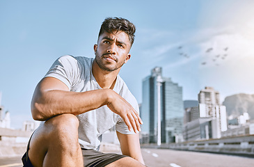 Image showing Exhausted, runner and fitness athlete taking a break after a morning cardio workout at sunrise. Tired, urban male jogger resting after exercise and kneeling in the city after a training marathon.