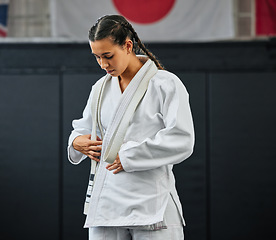 Image showing Mma, karate and self defense with a young woman getting ready in her gi or uniform for training, exercise and practice. Workout, sport and fighting with a female athlete standing in a gym or studio