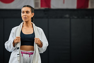 Image showing . Mma, training and martial arts with a sporty young female fighter getting ready for a fit, match or competition in her gi or uniform. Training, exercise and sparring with a woman standing in a gym.