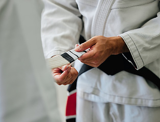 Image showing . Karate master tying a belt on a student in a dojo before practice. Closeup of a sensei help, prepare and assisting a beginner before exercise, workout and training in a sport club.