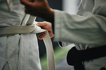 Image showing Karate learning, training and workout of a sport student and coach getting ready for a fight class. Defense expert hands tie a belt in a dojo, workout studio or wellness club about to work on fitness