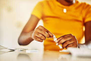 Image showing Hands of African female with HIV and Aids at home blood self test kit sitting at a desk waiting to check for results. Closeup of young afro woman with medicine or pills for a medical condition.