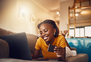 Image showing Online shopping young, happy and smiling African lady with bank, credit or gift card. Excited, comfortable and cheerful ethnic female typing on laptop searching, browsing and buying present from home