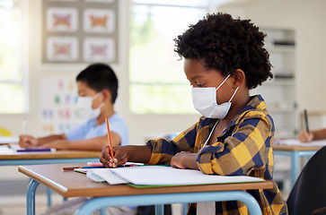 Image showing School student in class during covid pandemic for learning, education and study with mask for safety, protection and protocol. Little kindergarten, preschool or elementary kid writing in book at desk