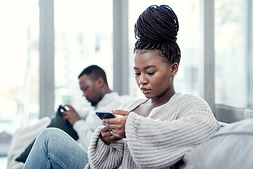 Image showing Angry, serious and annoyed woman giving her boyfriend the silent treatment or cold shoulder after a fight, argument or disagreement as a couple. Female reading a text and ignoring her husband at home