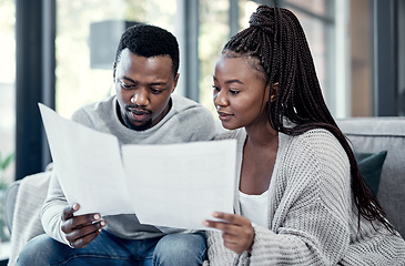 Image showing Married couple planning their finance and budget bills or papers together at home. Serious husband and young wife looking at household financial report information and insurance money plan