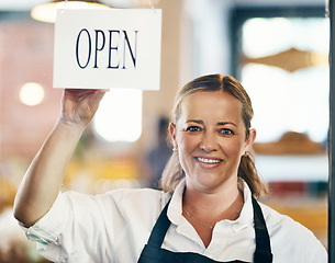 Image showing Cafe owner opening her new startup, store or welcoming customers to a restaurant. Caucasian manager reopening her business after closing down. Waitress holding open sign at window or entrance.