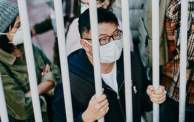 Image showing Sick, trapped young covid patient stuck in the city feeling like a prisoner, wearing a medical face mask. Foreign asian man in a crowd during a pandemic. Male following city healthcare safety rules.