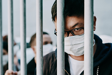 Image showing Depressed, upset or sad covid patient stuck in the city feeling like a prisoner, wearing a medical face mask. Foreign asian man in a crowd during pandemic holding area following city healthcare rules