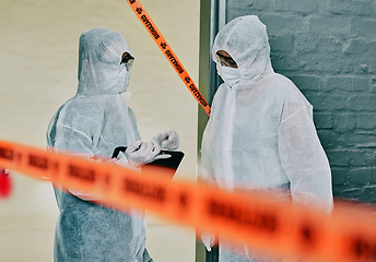 Image showing Forensic investigators collecting evidence at a murder scene in a building with barrier tape. Criminal researchers investigating a crime site and talking about the incident or case