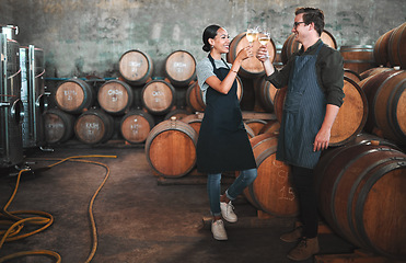 Image showing Wine distillery owners cheers glasses in the cellar standing by the barrels. Happy and celebrating business owners or sommeliers enjoying chardonnay or sauvignon blanc inside a winery