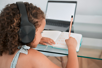 Image showing Home, school and education of a girl writing, learning and working or study online on a laptop. Child, internet and student using technology for elearning at the house while listening to podcast.