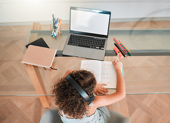 Image showing Education, distance learning child listening headphones and internet on laptop for online activity or a web teaching lesson at home. Smart student busy writing maths homework or test in a notebook