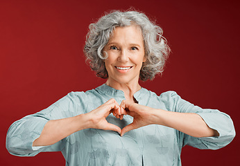 Image showing Love, heart and health retired woman with loving emoji sign, icon or symbol showing care or affection on red valentines day studio background. Grey, senior or pensioner with a trendy emoticon pose