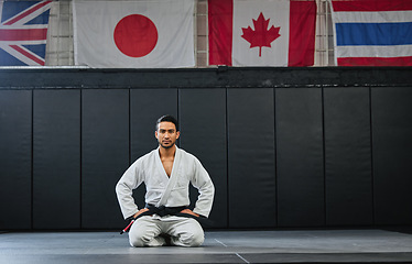 Image showing Martial arts, black belt and sitting fighter inside dojo for training. Defence club, champion or coach exercising in his sportswear. Karate or mma man looking with focus and discipline at the gym.