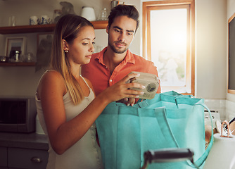 Image showing Wrong order of grocery, food and kitchen products bought by a couple for home cook dinner or lunch. Unhappy male and female unpacking diet cooking supplies, ingredients or groceries from shopping bag