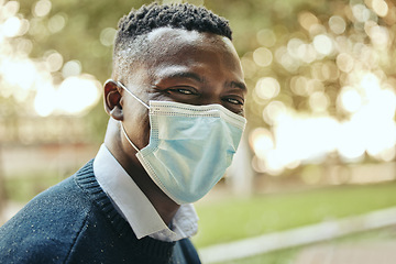Image showing Face, mask and covid of a black businessman in the city for health and safety in the outdoors. Portrait of a happy man in a pandemic alone outside in nature with mockup background.
