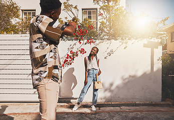 Image showing Photographer with model for summer fashion photography taking photo, posing and smiling for portrait shot with lens flare. African creative freelancer taking picture of young influencer woman outside