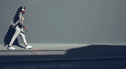 Image showing Working black woman in marketing business on wall background walking, listening to podcast, radio or music with headphones. Travel to office building, copy space banner and company mockup content.