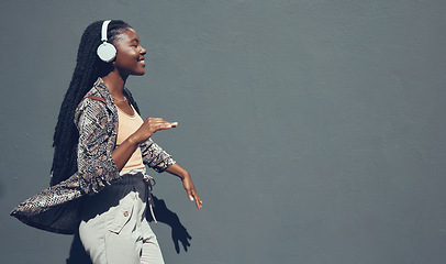 Image showing Music, university and college dance student dancing and listening to podcast or radio on headphone walking past campus. Copy space banner for education mock up content on grey wall background.