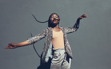 Image showing Fashion, style and trendy black woman against a gray background wall in a city, town and downtown. Street beauty model with funky, cool and hipster hair in edgy motion or movement expression outdoors