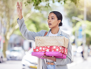 Image showing Woman holding gift and calling for a taxi in the street for travel to a birthday, anniversary or congratulation party. City girl standing in the road after shopping for a present for friend or family