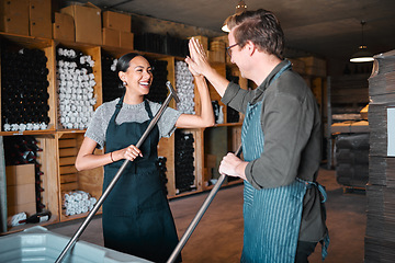 Image showing Success, partnership and collaboration business partner high five while working together in a wine distillery. Winemaker workers excited and having fun pressing grapes in the wine industry together