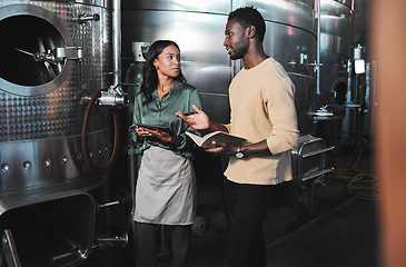 Image showing Wine production workers using alcohol machine or distillery equipment in warehouse winery. Business sommelier expert woman and man talking and working on quality control maintenance with a checklist