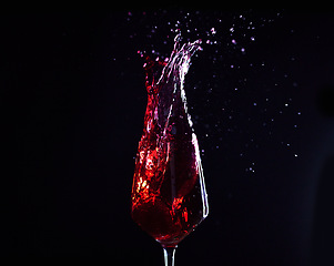 Image showing Wine, alcohol or drink glass and splash on black studio background for celebration, cheers or restaurant toast. Zoom, red creative texture or fruit beverage in liquid motion at event or birthday