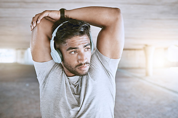 Image showing Fitness man training with headphones stretching, listening to music or a motivation podcast with lens flare in urban city. Sports person with an online audio for his warmup morning workout exercise