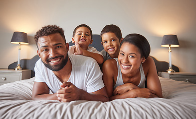 Image showing Portrait of happy black family on a bed with children, carefree, relaxing and playing in a bedroom together. Young parents enjoying morning bonding, being playful and showing affection