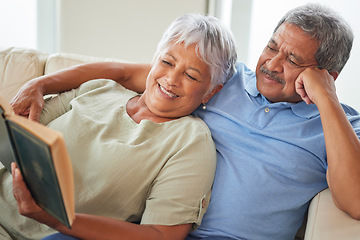 Image showing Relax, happy and senior couple reading a book together at home while relaxing and smiling on a couch. Mature or old lovers learning and resting while enjoying a story as entertainment in the house