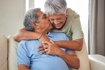 Image showing Happy senior couple kiss, hug and smile with love while relax on the sofa in the living room at home. Playful, fun man and woman laughing, smiling and enjoying retirement life together in their house