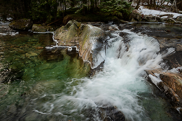 Image showing Cascading Mountain Stream With Snowy Banks in a Forested Winter 