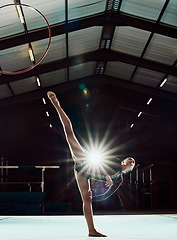 Image showing Girl, art stage and body performance for gymnastic balance and competition practice studio. Acrobat sports and dancer woman with hula hoop ring stretching legs in front of flare light effect.