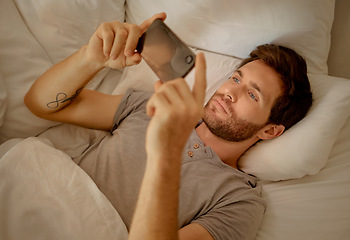 Image showing Young man relaxing in bed with phone watch, movie, series or online social media videos on an app. Browsing the internet news with 5g technology on cellphone or smartphone play a game in the bedroom