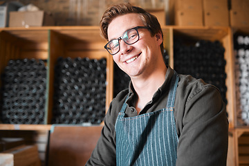 Image showing Happy, smile and proud wine, warehouse or manufacturing worker wearing glasses in a cellar with a bottle collection on display. Winery manager or employee in the alcohol industry or distillery