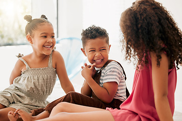 Image showing Happy, cheerful and laughing children sitting together and having fun at a playdate. Adorable boy and girls enjoying their time together at home. Siblings, sisters and brother bonding and playing