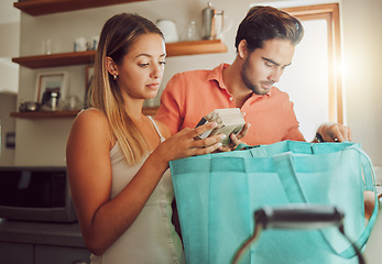 Image showing Groceries, plastic free and healthy couple unpacking after returning home from a shopping trip. Serious man and woman with reusable bag with food and ingredients while reading nutritional labels