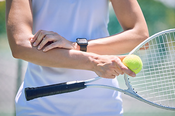 Image showing Sports, arm pain and tennis player with a racket and ball standing on a court during for a match. Closeup of a health, strong and professional athlete with equipment touching a medical elbow injury.