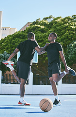 Image showing Fit, active and sporty young basketball players stretch or warm up their legs on a basketball court. Determined male athletes prepare muscle fitness before practicing or training at a sports venue