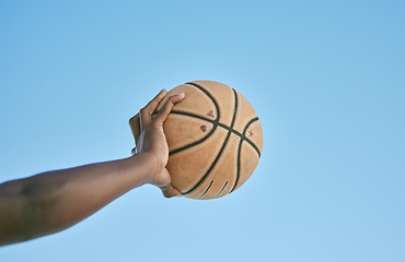 Image showing Basketball, active and sports man hand holding ball showing victory, power or athletic fitness from below with blue sky background. Player, black man or athlete arm practicing for professional league