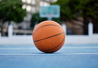 Image showing Basketball on the floor of a sports court during training for a game in summer outdoors. Closeup of orange ball for athlete team to practice their strategy for fitness and exercise in outside stadium