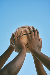 Image showing Teamwork, support and hands holding a basketball at the start of a league match or competition against a blue sky. Closeup of African American athletes or sportsmen playing and practicing with a ball